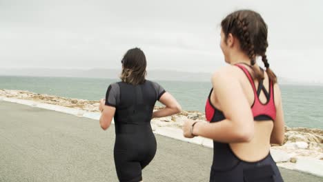 vista trasera del entrenamiento de triatletas para maratón cerca del mar