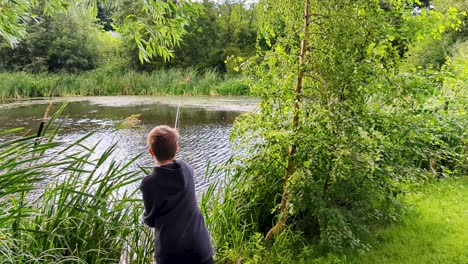 4k-60fps-Junge-Wirft-Sein-Angelgerät-In-Einen-Baum,-Während-Er-In-Einem-Teich-In-Dänemark,-Skandinavien-Fischt