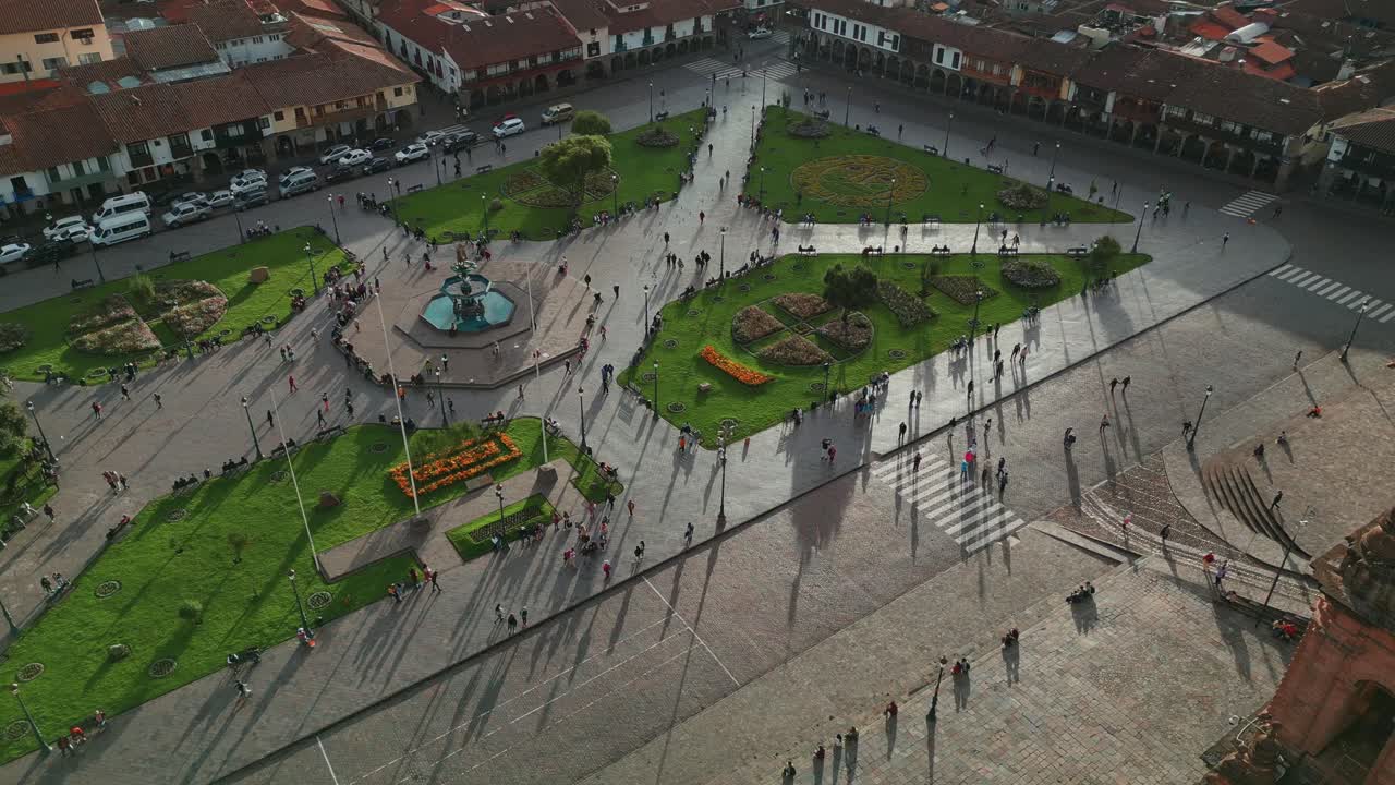 disfruta de una vista panorámica descendente, que muestra la bulliciosa plaza principal y las icónicas torres de la iglesia en cusco, con personas paseando y disfrutando del día