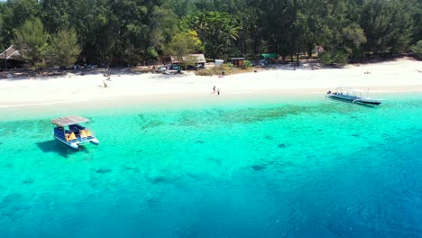 Touring-boat-anchoring-on-calm-clear-water-of-blue-azure-lagoon-washing-white-sandy-beach-of-tropical-island-with-trees-in-Myanmar