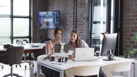 Asian-woman-and-young-Caucasian-woman-examine-business-documents-in-modern-office