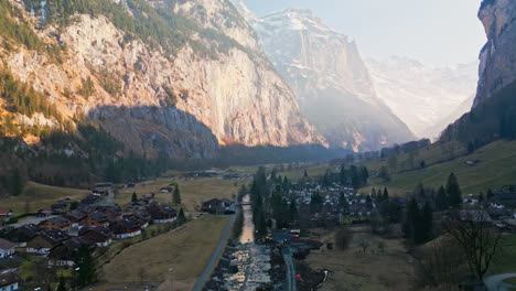 El-Dron-Asciende-Por-Encima-De-Treee-Para-Revelar-El-Amplio-Cañón-Y-La-Ciudad-De-Lauterbrunnen,-Suiza,-En-La-Base-En-Las-Sombras.