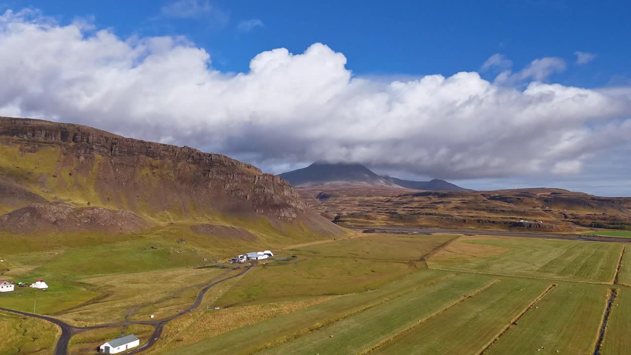 Scenic hill volcanic landscape with rolling clouds of north Iceland in autumn with farm house and fields in foreground. Drone hyperlapse