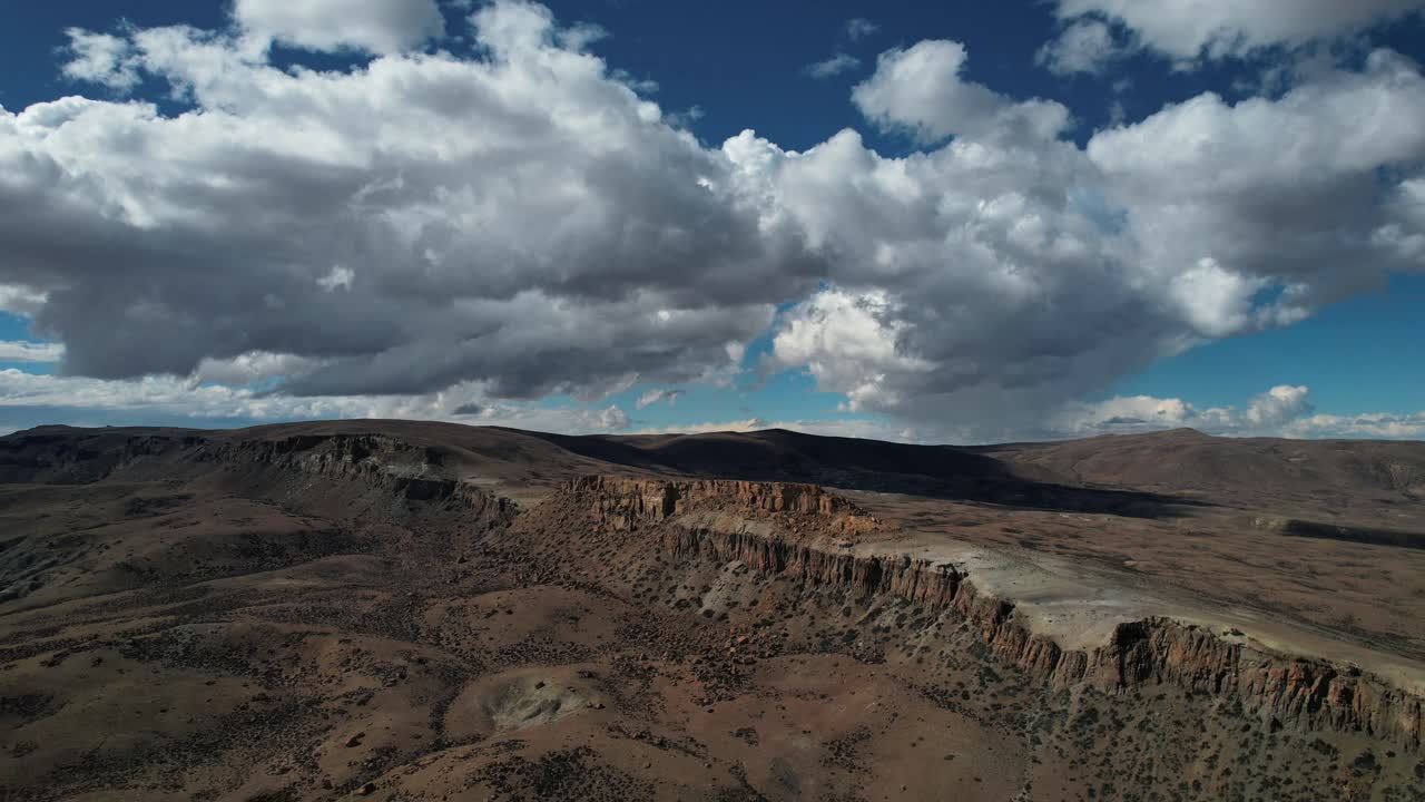 Paesaggio aereo della Patagonia con nuvole drammatiche su una scogliera rocciosa.