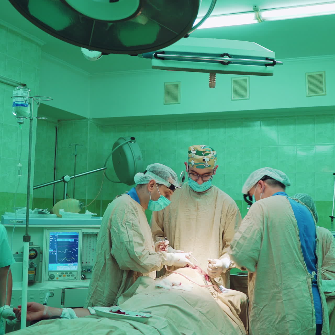 Male surgeons and assistants women during the operation in clinic. Doctor's team wearing medical uniform and masks performing operation in hospital operating theater on patient.