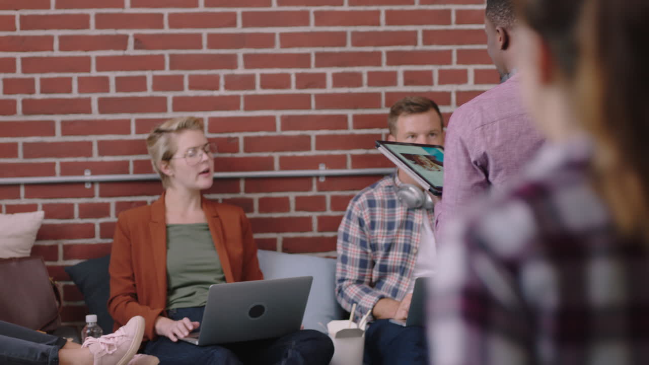 디지털 태블릿 컴퓨터를 사용하는 젊은 아프리카계 미국인 사업가 마케팅 전략 팀 리더 아이디어를 공유하는 다양한 사업가들이 스타트업 회사 사무실에서 협력합니다.