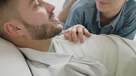 Close-Up-View-Of-Young-Couple-Lying-On-Sofa-Talking-And-Caressing-Each-Other