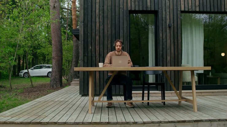 Uomo che lavora all'aperto su una terrazza di legno