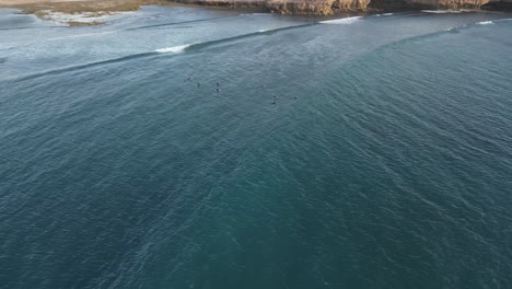 aerial top down shot of surfer surfing on water in australia during sunset time with sun rays