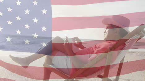 animación de la bandera de los estados unidos de américa sobre un hombre de dos razas que usa un teléfono inteligente en la playa