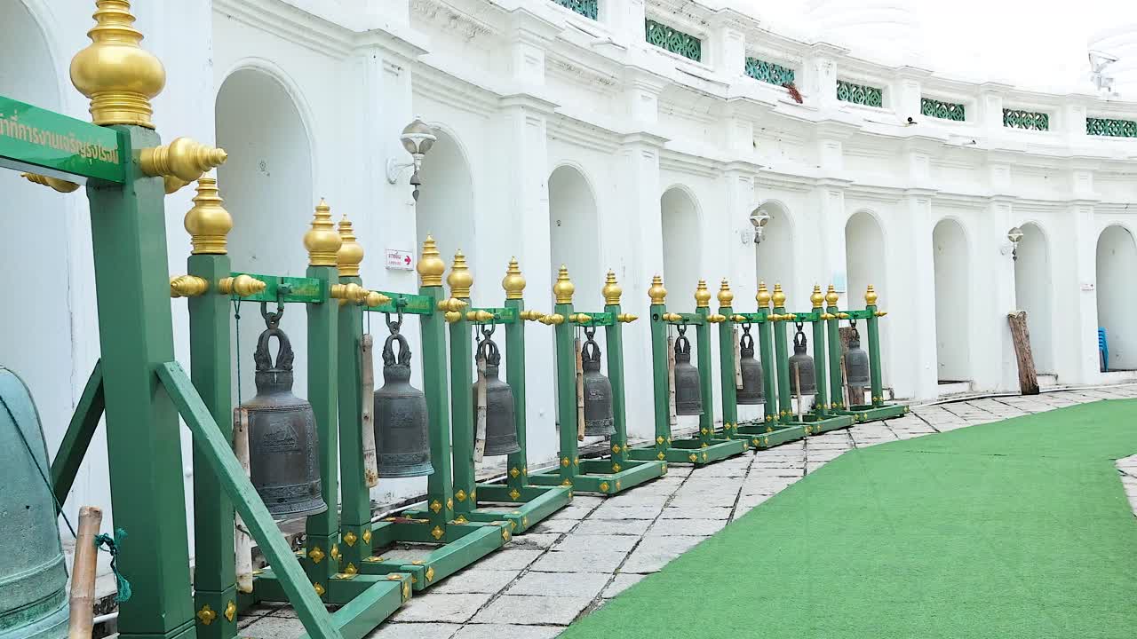 부드러운 낮빛 아래, 종으로 둘러싸인 성전 복도를 따라 는 사람의 조용한 장면