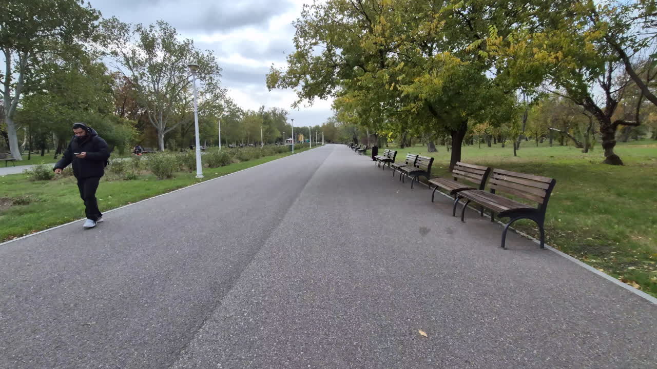 Point of view shot from a bicycle riding through a park lined with autumn trees and benches