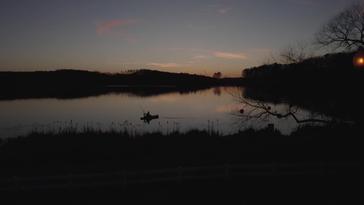 silhouette drone -kuva kalastajasta järvellä auringonlaskun aikaan