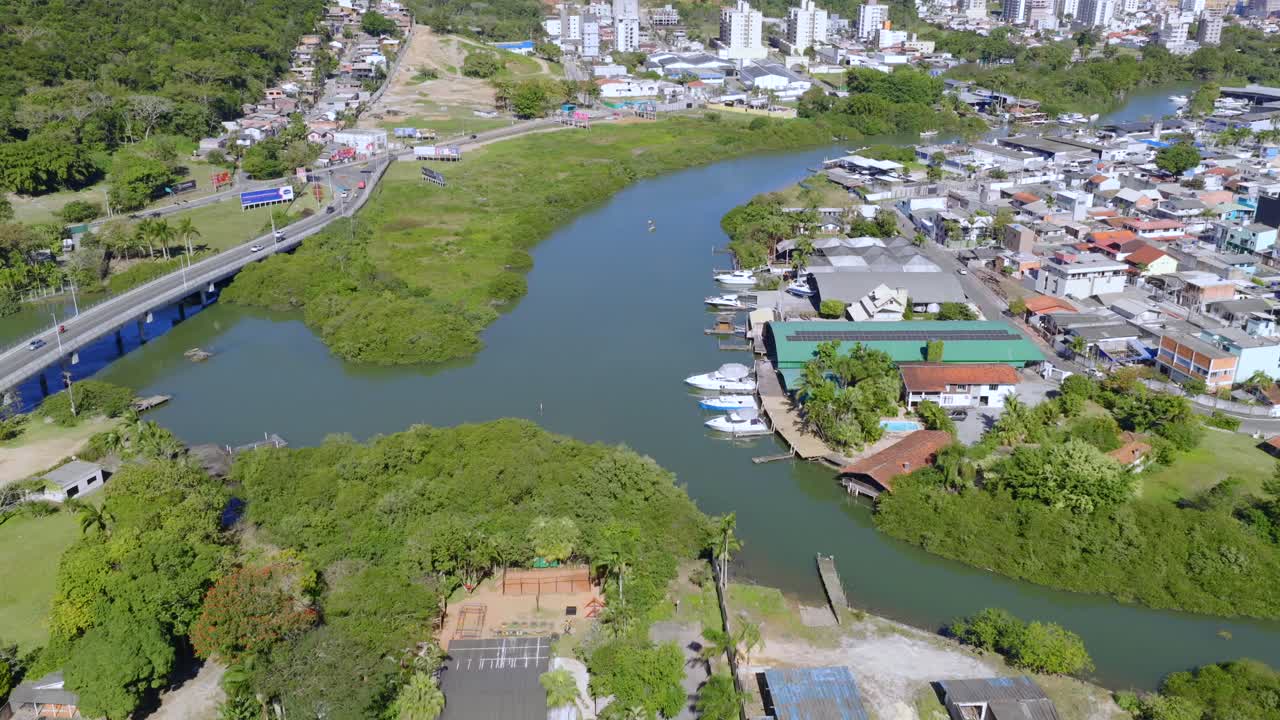 Tilted aerial fly over the Camboriú River delta with green vegetation and houses near water channels, Balneário Camboriú, Santa Catarina, Brazil
