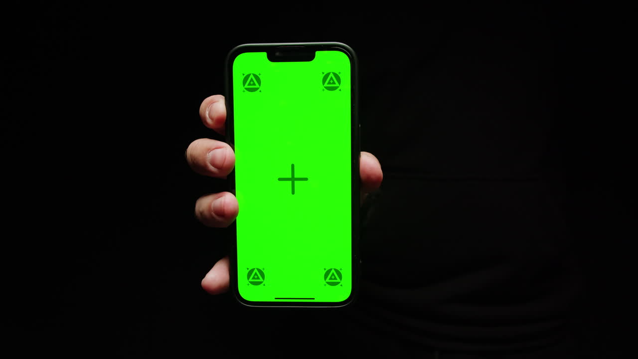 Smartphone with chroma key screen on black background close-up. Green screen on mobile phone in hand.