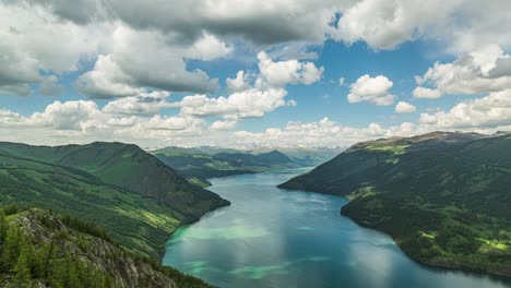 lapso de tiempo de nubes blancas esponjosas que fluyen sobre un enorme lago en medio de montañas verdes en un brillante día de verano azul cielo