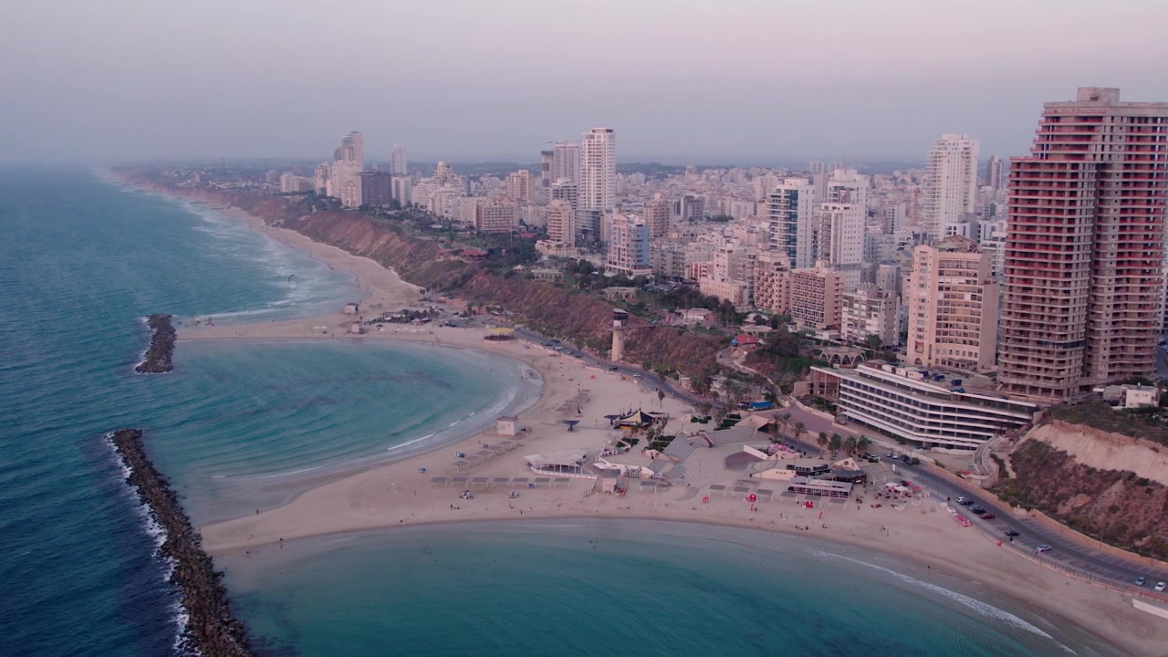 Vista aerea di una città costiera con spiaggia e grattacieli al tramonto