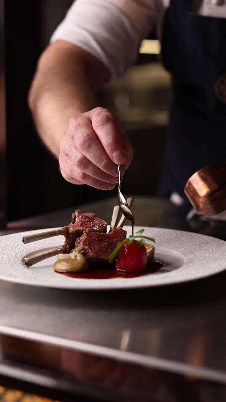Chef che impiattano costolette d'agnello gourmet in una cucina professionale