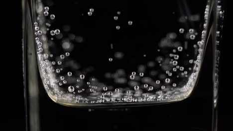 close up of mineral water bubbles in the glass. macro shop of carbonated fresh sparkling drink with oxygen balls on dark background