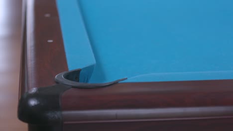 man scratching cue ball in corner pocket on blue billiards table