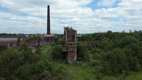 abandoned old overgrown coal mine industrial rusting pit wheel buildings aerial view rising front shot