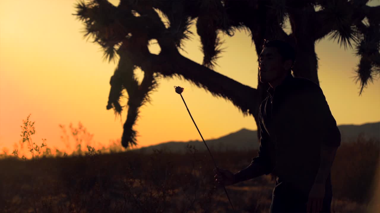 silueta en cámara lenta de un hombre soplando fuego en el desierto al atardecer