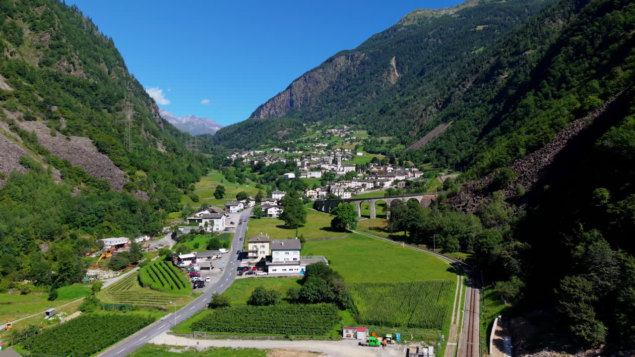 Aerial view of Swiss village in green valley with clear sky and mountains