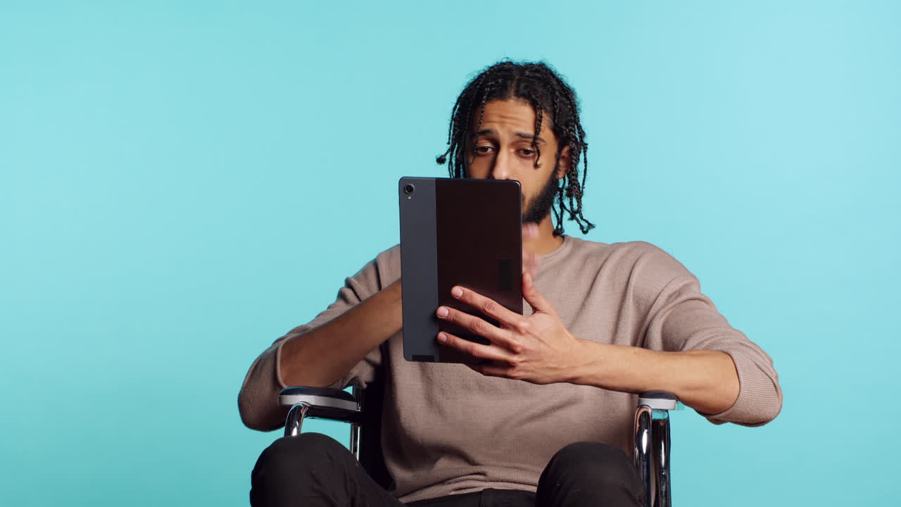 Person with paraplegia using tablet for social media, studio background