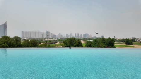 sunny day at vida emirates hills pool with trees and skyscrapers