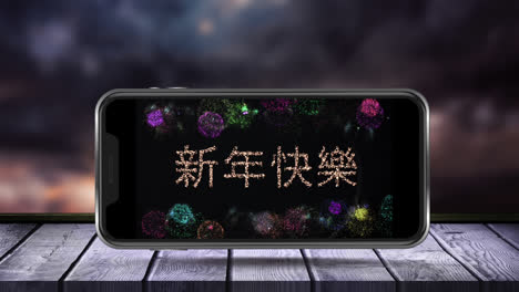 digital animation of happy new year text in chinese and fireworks exploding on smartphone