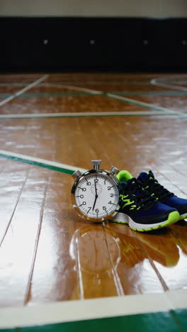 stopwatch and running shoes on a sports floor