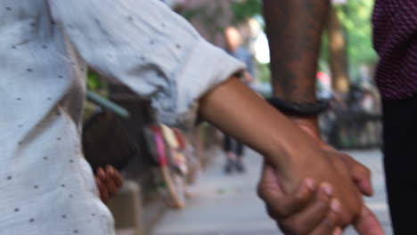 Close-Up-Rear-View-Of-Couple-Walking-Along-Street-Holding-Hands