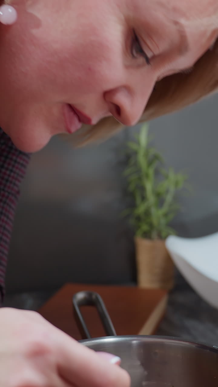 mujer elegante con cabello rubio corto cocinando en una cocina moderna, la mano descansando en el cuello adornada con una elegante pulsera de cuentas rosadas, centrada en la preparación de comidas y tofu en la tabla de corte