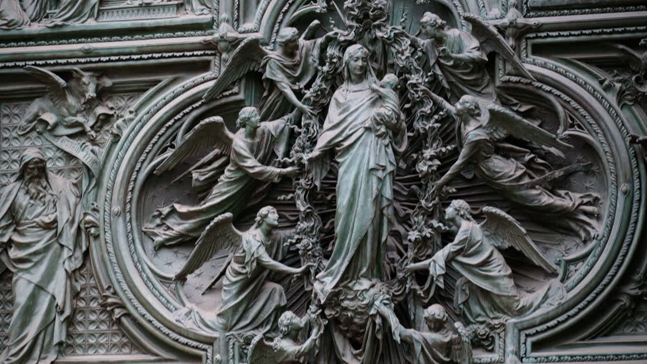 Close up of a detailed relief sculpture of the Virgin Mary holding the infant Jesus, surrounded by multiple angels on the Duomo in Milan, Italy