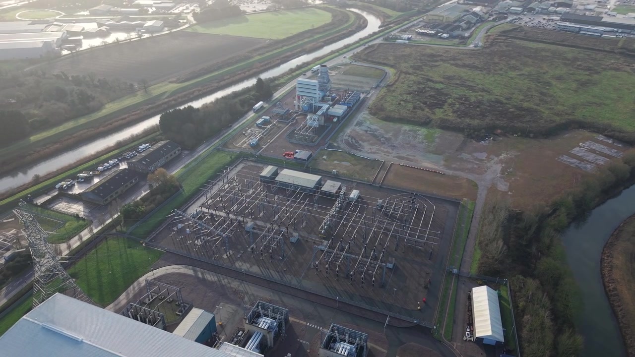 Scenic drone flight over a major gas powered electricity generation site in sunny conditions