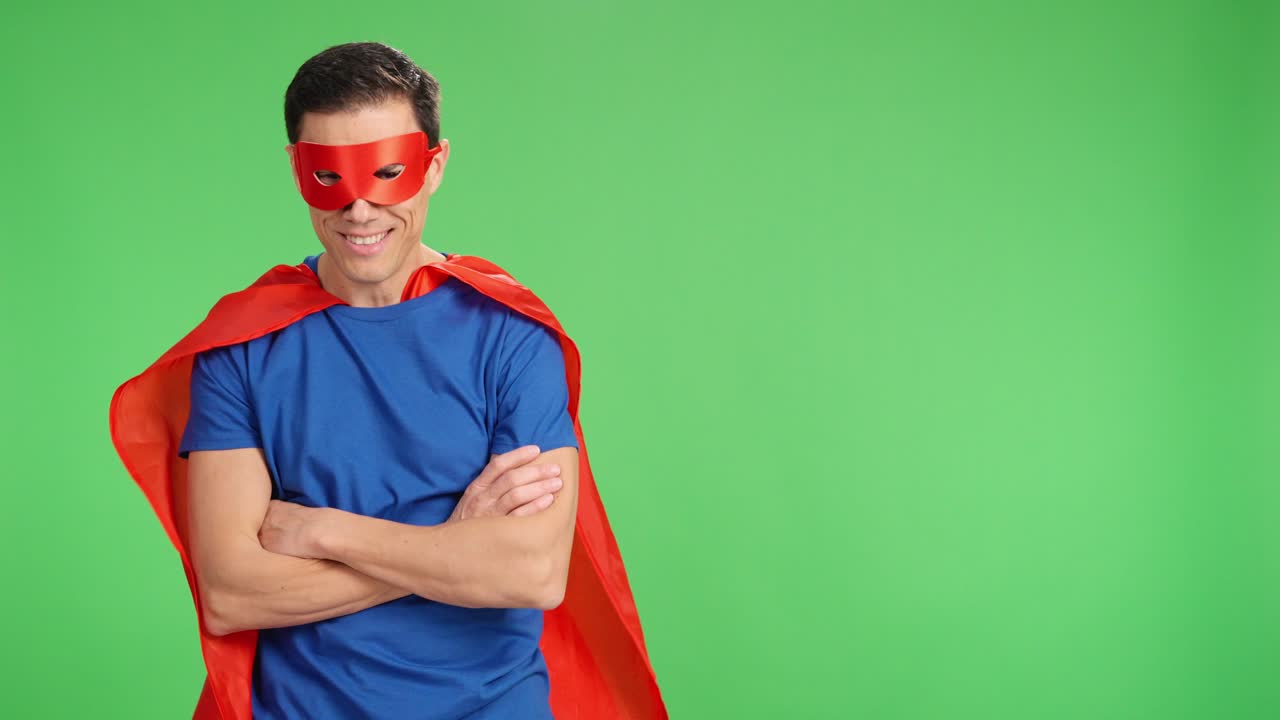 Superhero posing with crossed arms and showing determination on green screen