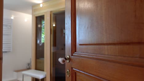 slow establishing shot of a door revealing a small wooden sauna within a house