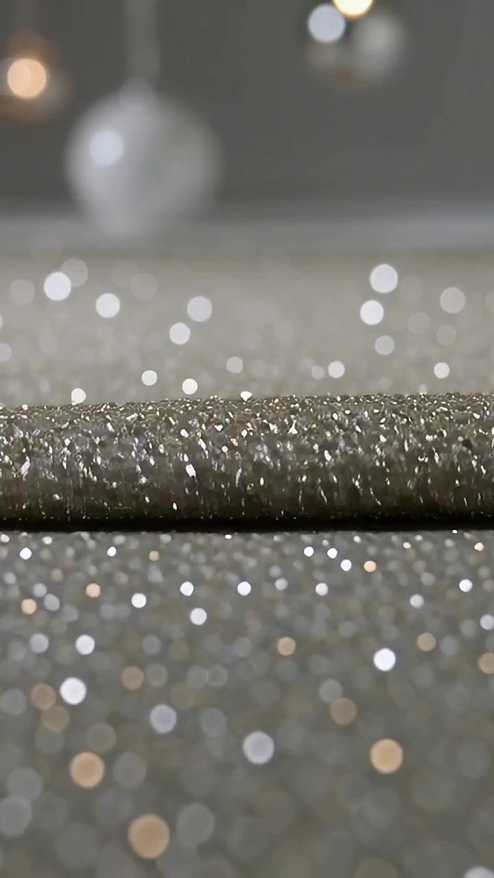 Vertical video: Light hitting glitter roll sending glitter upward over table with spheres for bokeh