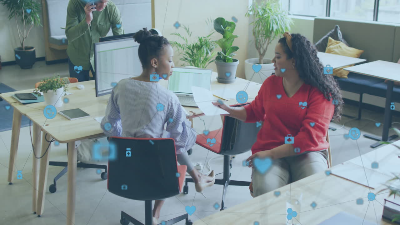 Animation of network of digital icons against two diverse women discussing over document at office