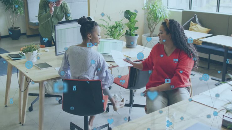 Animation of network of digital icons against two diverse women discussing over document at office