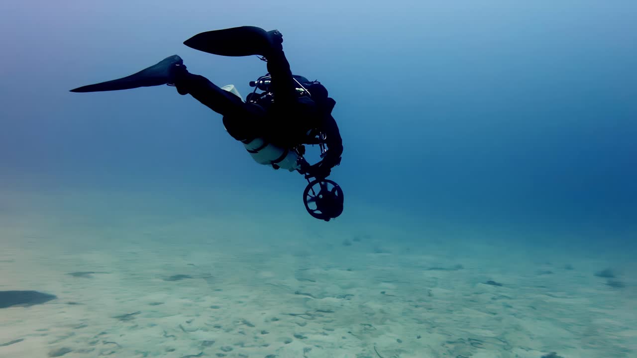 Underwater Adventure in Mediterranean Sea Near Malta Featuring Technical Diver with Scooter Propulsion Passing Over Sunken Wreckage in Crystal Blue Water During Bright Summer Day with Wide Angle View
