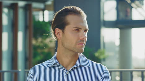 portrait of a smiling young man in a striped shirt outdoors