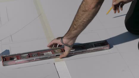 a construction site male worker using levels for scaling on white surface