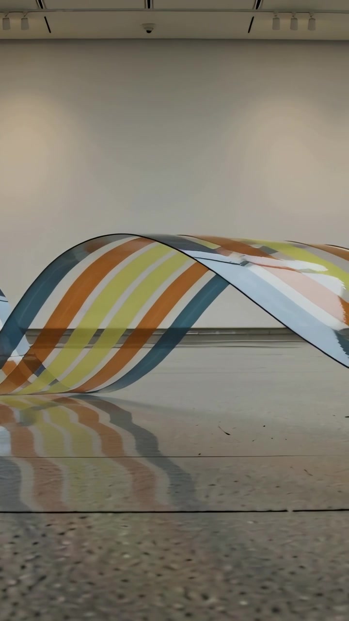 Vertical video: Panning low camera revealing striped ribbon on gallery floor, showing reflection