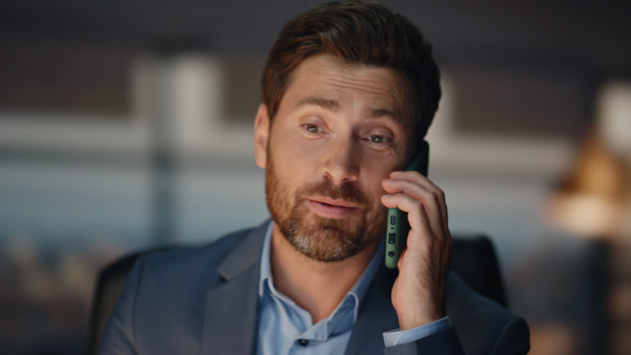 Closeup happy businessman calling mobile phone at evening office. Boss talking