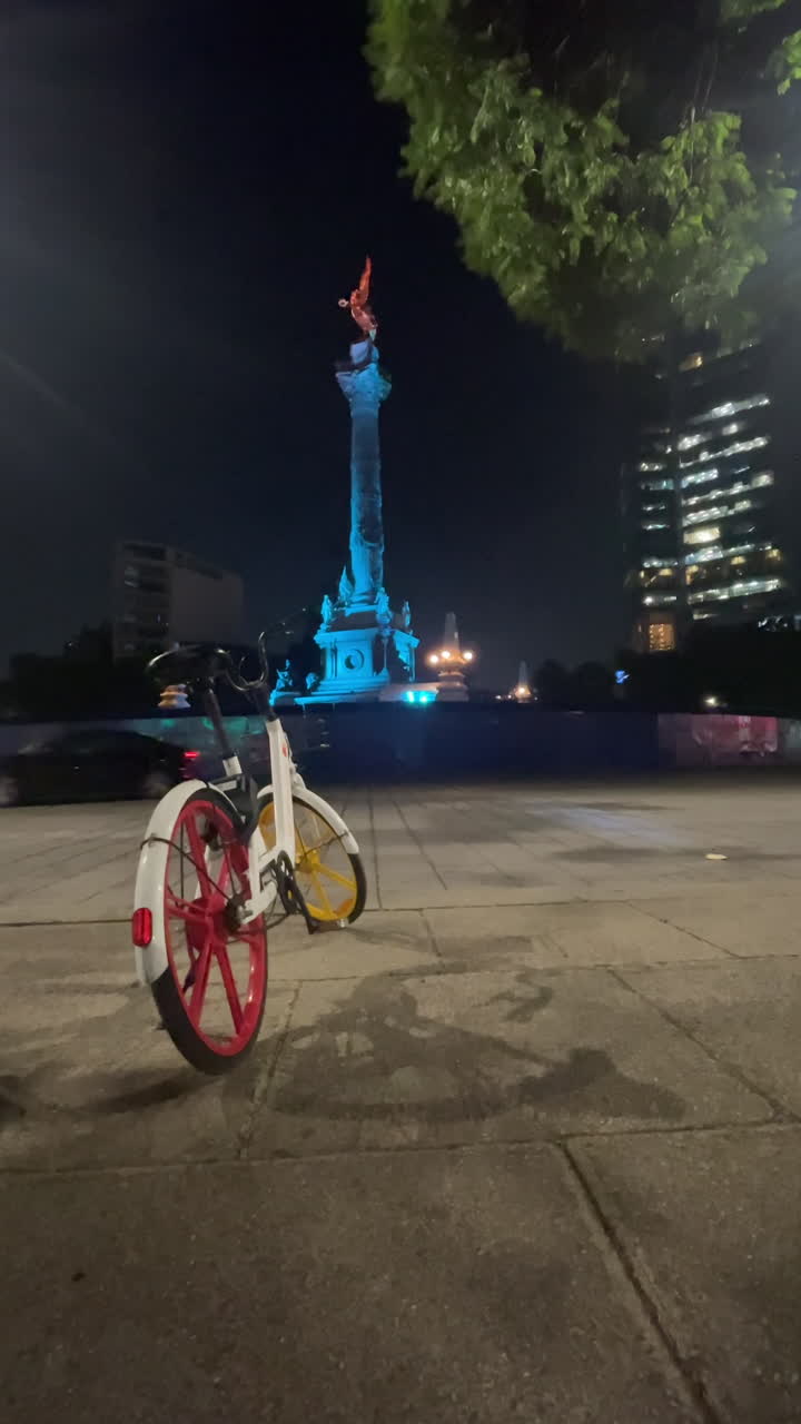 Independence Angel at night with bicycle in foreground and car passing by in Mexico City central. DF vertical