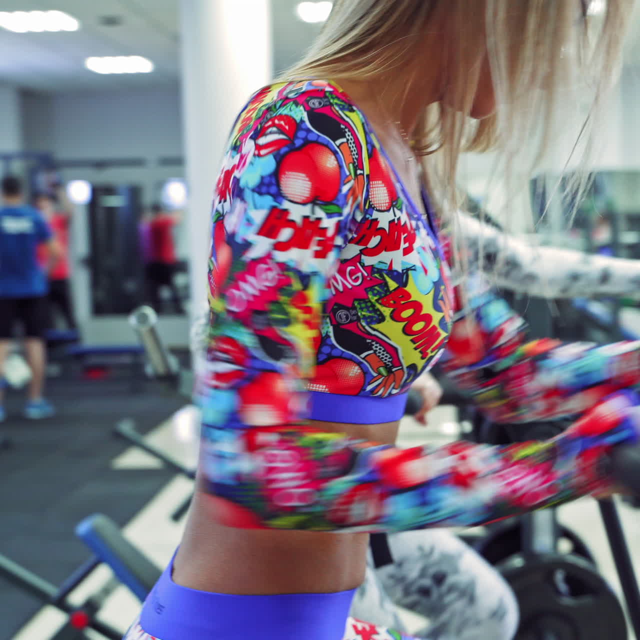 Two sexy young women in sport clothes doing working out on exercise bikes at the gym. Slim females exercising on bicycle indoors. Close-up