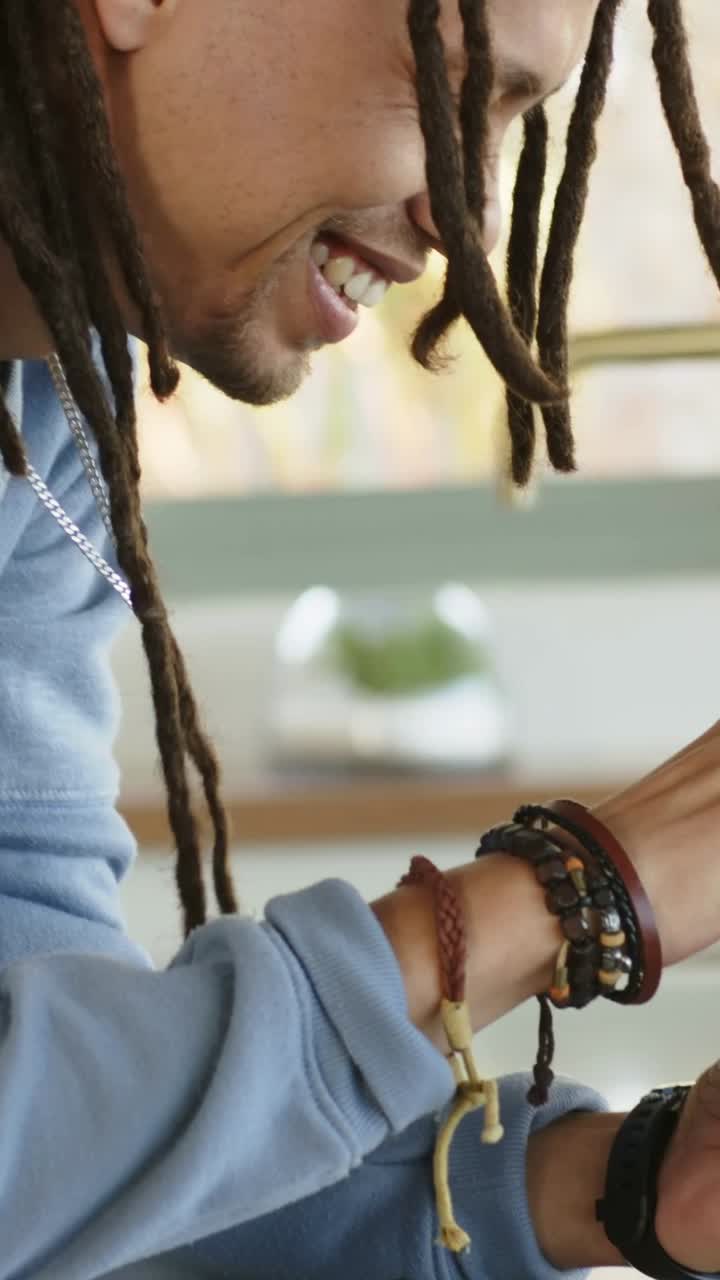 Video verticale: Uomo sorridente in blu appoggiato, con le mani che sollevano il telefono e digitano in cucina, con spazio per il testo.