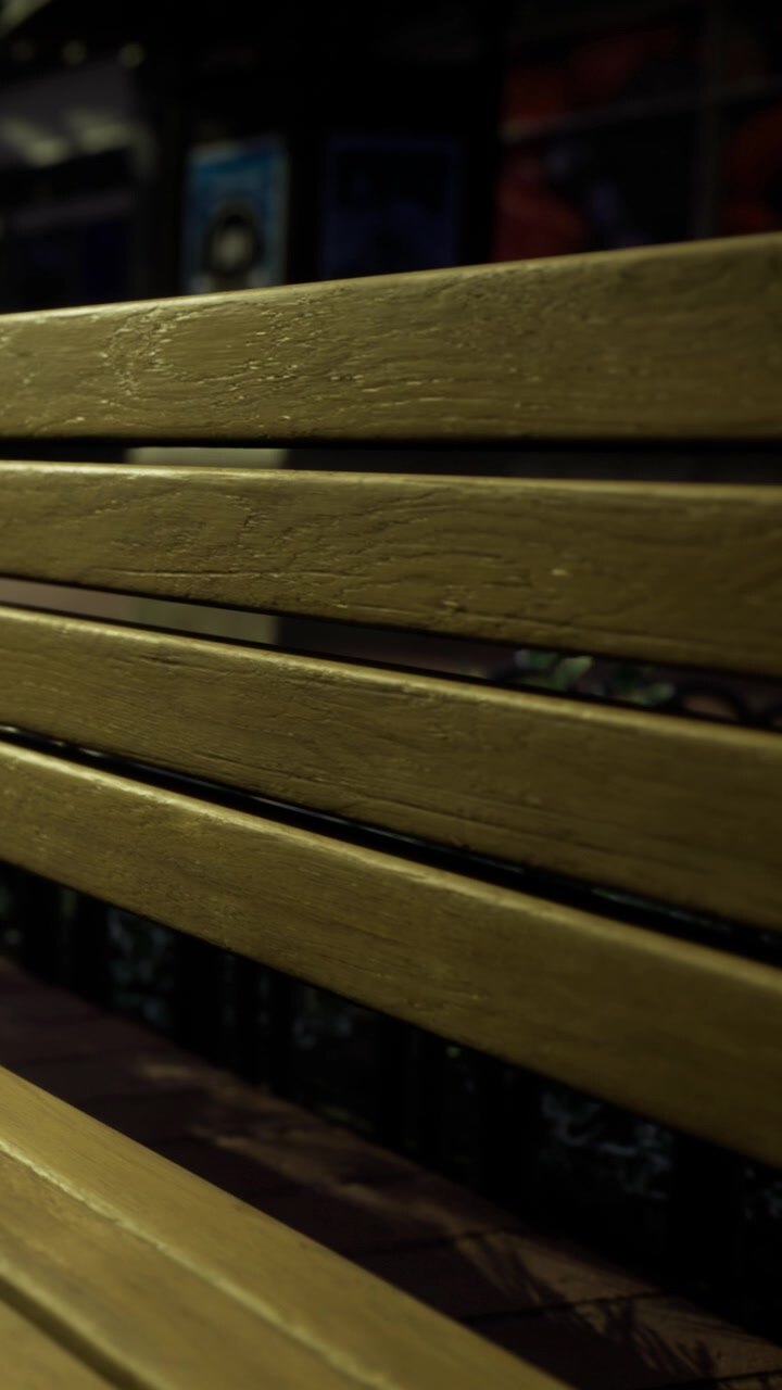 Panchina di legno in un parco di notte con illuminazione soffusa e ombre.