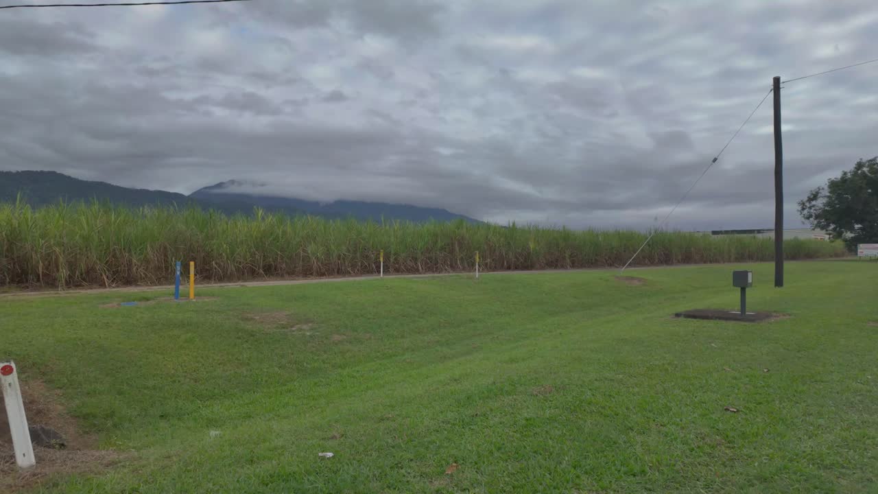 4K Sweeping view of a sugarcane plantation with mountains in the background covered with clouds in North Queensland in Australia
